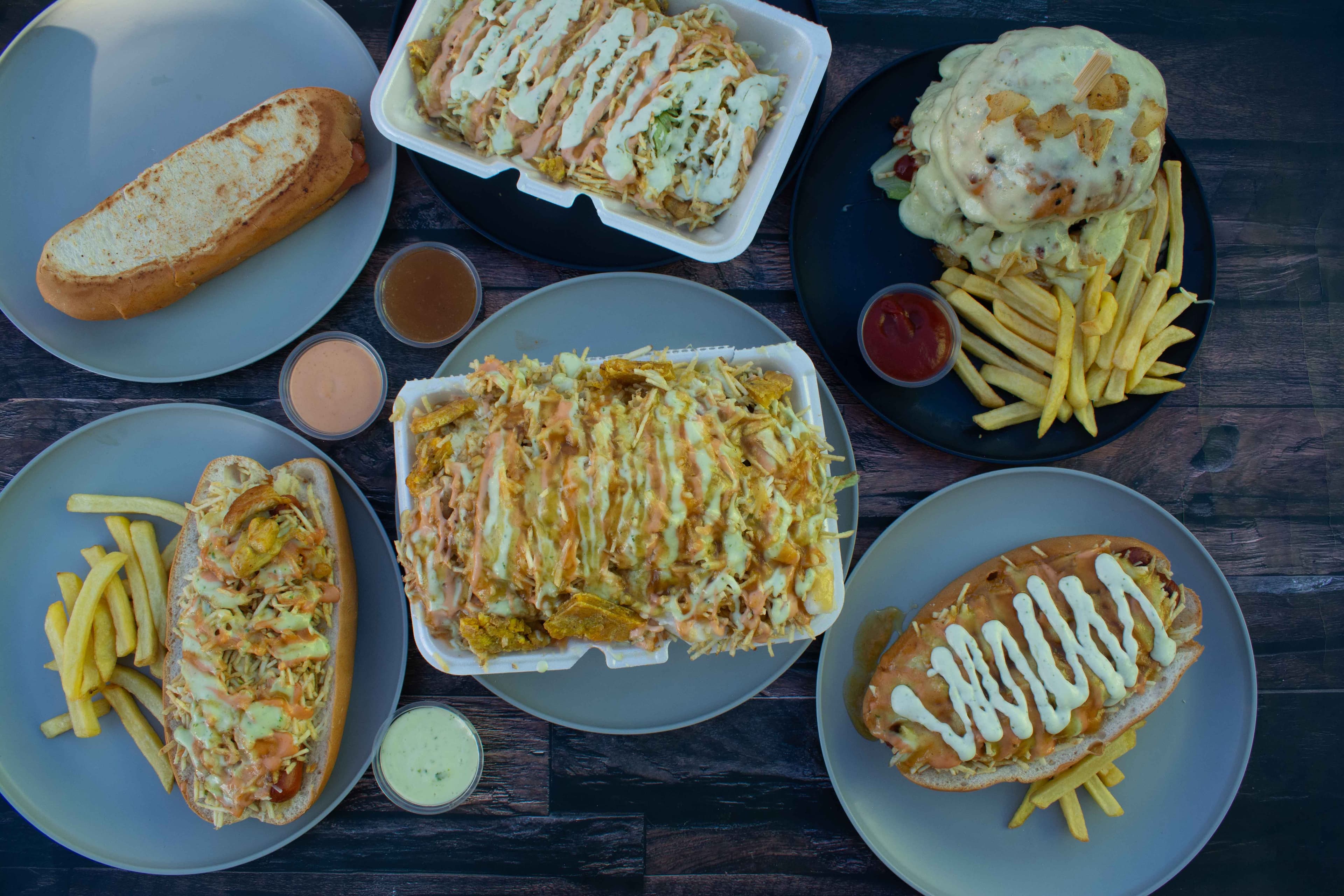 Mesa servida con hamburguesas, perros y platos de La Marimonda