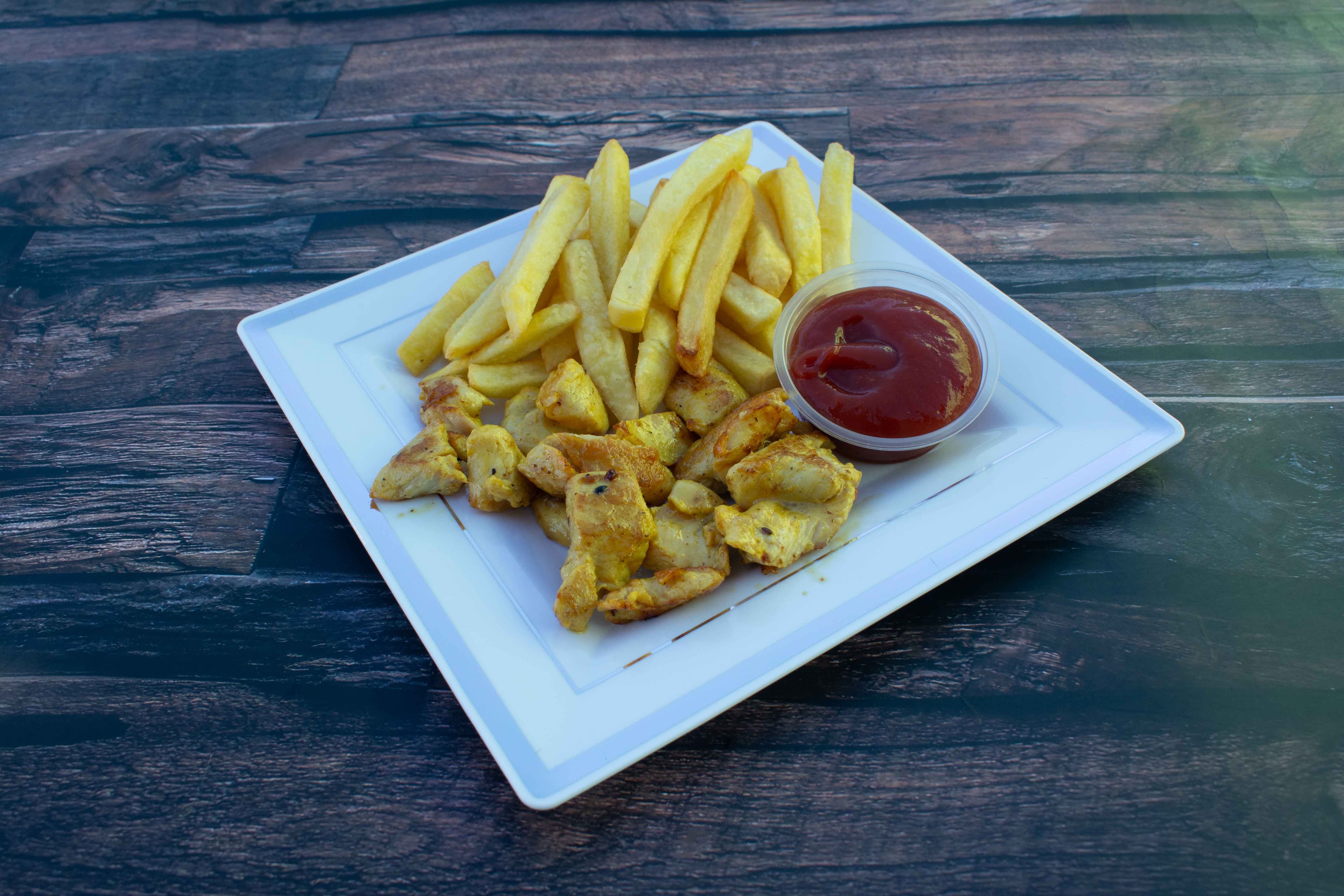 Papas a la francesa con trocitos de pollo y ketchup